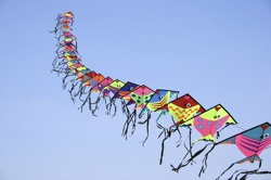 a line of kites in a blue sky
