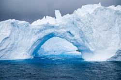 A huge iceberg with an arch in the middle