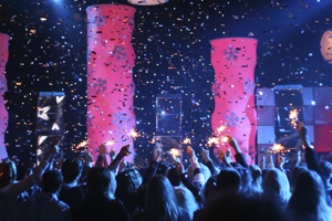 a crowd in a nightclub with sparklers, and confetti in the air