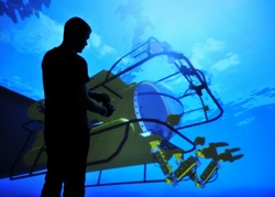 A man silhouetted in front of a large image of a simulated submarine
