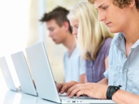 three young people sit at laptops