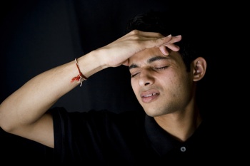 a magician touches his forehead as he concentrates