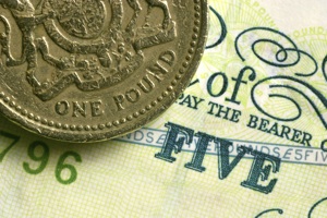 a pound coin on top of a five-pound note