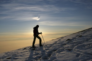 A hiker walks through snow on a hillside