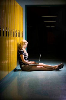 A girl studying with a laptop against lockers