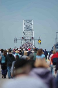 Lots of people going one way on a bridge