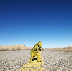 A plastic dinosaur looks menacing on a desert road