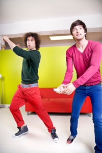 two young men playing video games with wireless controllers