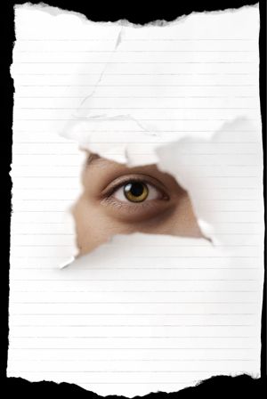 An eye looking through a hole in paper