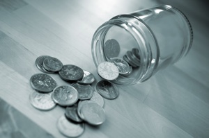 A tipped over coin jar with 10p coins spilling out