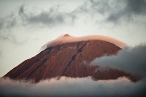 a mountain with red soil rises from the sea